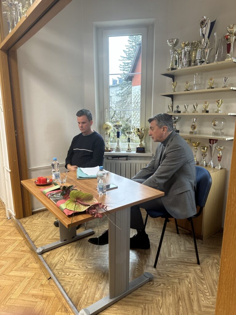Slika prikazuje člana Roka Janežiča, kot voditelja pogovora in gospoda bivšega predsednika Boruta Pahorja v pogovoru.